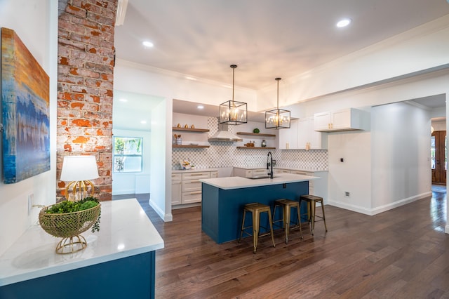 kitchen with a center island with sink, decorative light fixtures, decorative backsplash, and white cabinetry