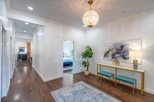 corridor featuring a notable chandelier, dark hardwood / wood-style flooring, and ornamental molding