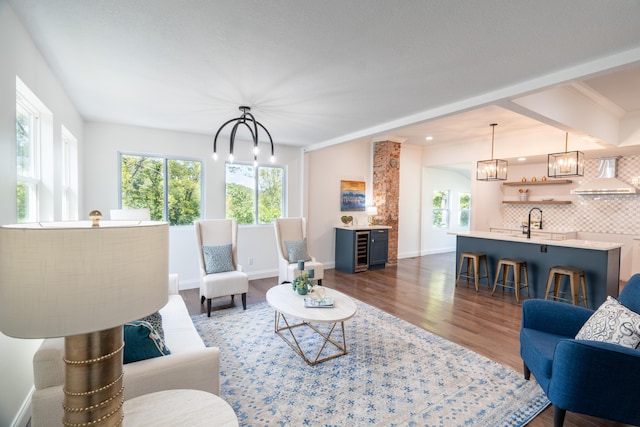 living room with a chandelier, dark hardwood / wood-style flooring, wine cooler, and sink