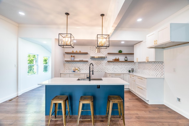 kitchen featuring white cabinets, a center island with sink, and a kitchen bar