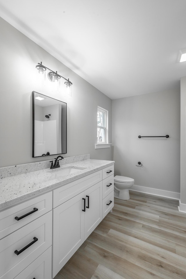 bathroom with vanity, toilet, wood-type flooring, and a shower