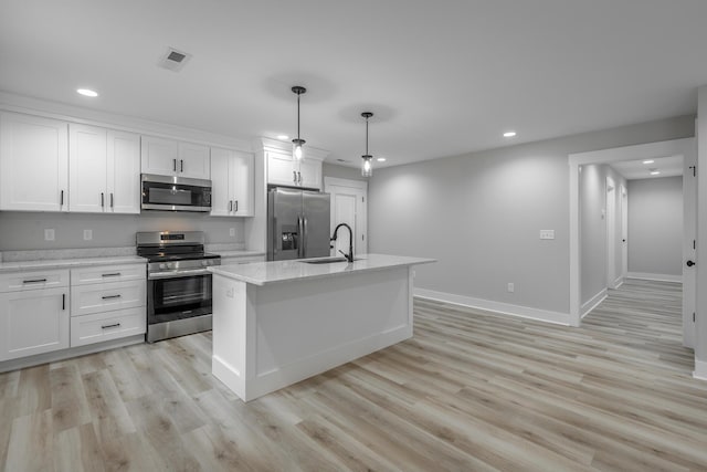 kitchen with white cabinets, an island with sink, decorative light fixtures, and appliances with stainless steel finishes