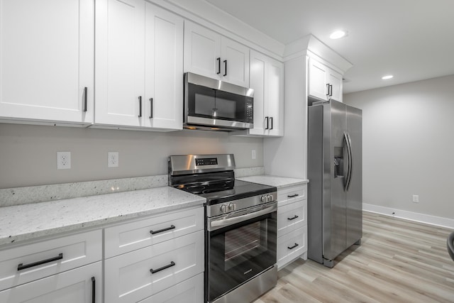 kitchen with light hardwood / wood-style floors, light stone countertops, white cabinetry, and stainless steel appliances