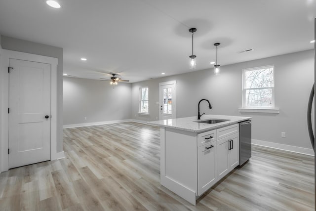 kitchen with pendant lighting, sink, ceiling fan, an island with sink, and white cabinetry