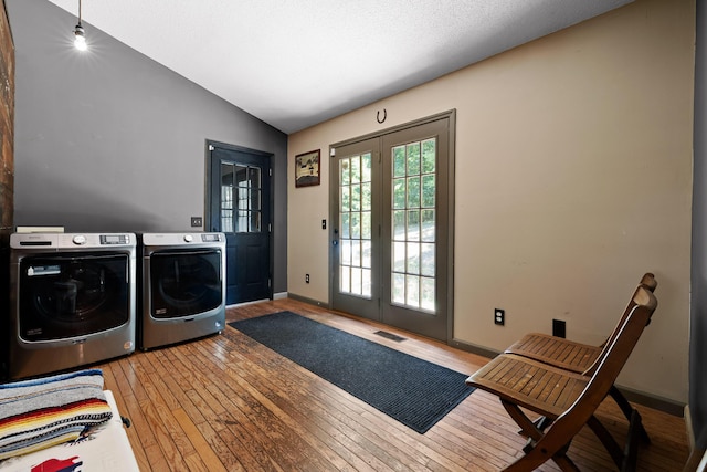 clothes washing area with washer and clothes dryer, hardwood / wood-style floors, and french doors