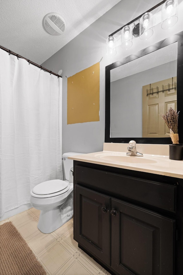 bathroom with vanity, a textured ceiling, and toilet