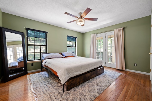 bedroom featuring access to outside, a textured ceiling, hardwood / wood-style flooring, and ceiling fan