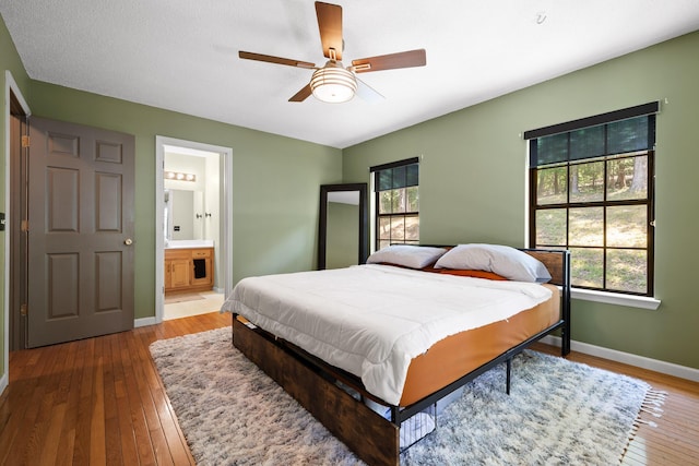 bedroom with ceiling fan, ensuite bathroom, and hardwood / wood-style flooring