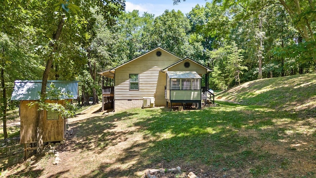 back of property featuring a sunroom, central air condition unit, and a lawn