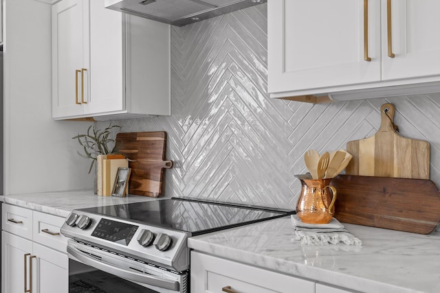 kitchen featuring decorative backsplash, light stone counters, wall chimney exhaust hood, white cabinetry, and stainless steel range with electric cooktop