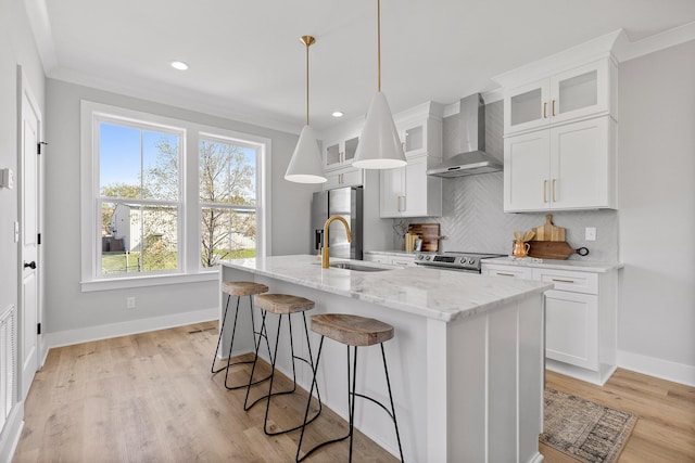 kitchen with wall chimney exhaust hood, an island with sink, appliances with stainless steel finishes, tasteful backsplash, and white cabinetry