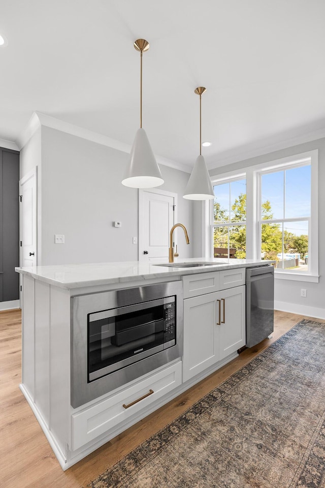 kitchen with pendant lighting, crown molding, sink, appliances with stainless steel finishes, and white cabinetry