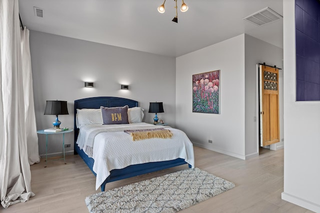 bedroom featuring a barn door and light hardwood / wood-style flooring