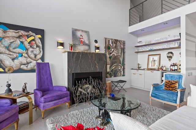 living room with a fireplace, light tile patterned floors, a high ceiling, and bar