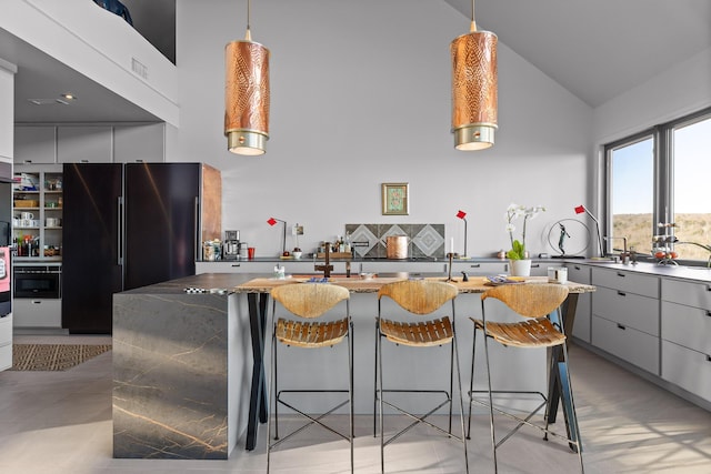 kitchen with decorative light fixtures, white cabinetry, refrigerator, and vaulted ceiling