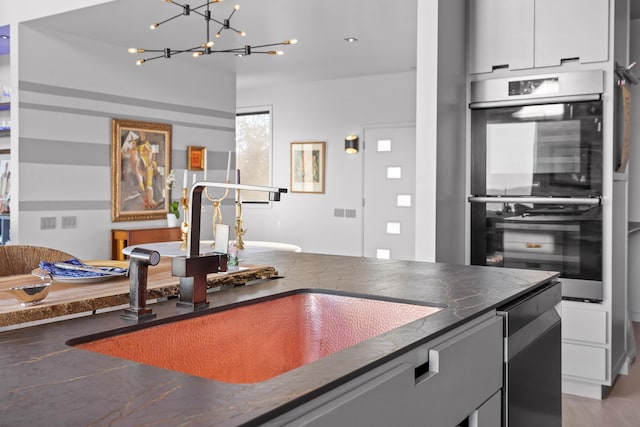 kitchen featuring sink, white cabinetry, stainless steel double oven, and wood-type flooring