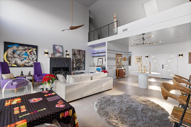 living room with a premium fireplace, a towering ceiling, and a chandelier