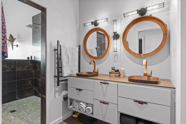 bathroom with tiled shower and vanity