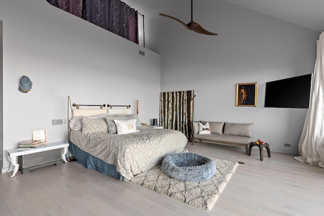 bedroom with light wood-type flooring and high vaulted ceiling