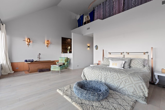 bedroom with high vaulted ceiling and light hardwood / wood-style flooring