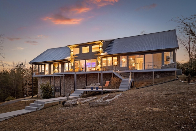 back house at dusk with a sunroom and central air condition unit