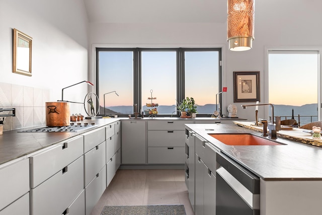 kitchen featuring dishwasher, sink, backsplash, gray cabinets, and stainless steel gas stovetop