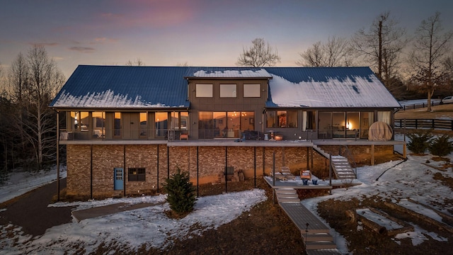 snow covered rear of property with a balcony