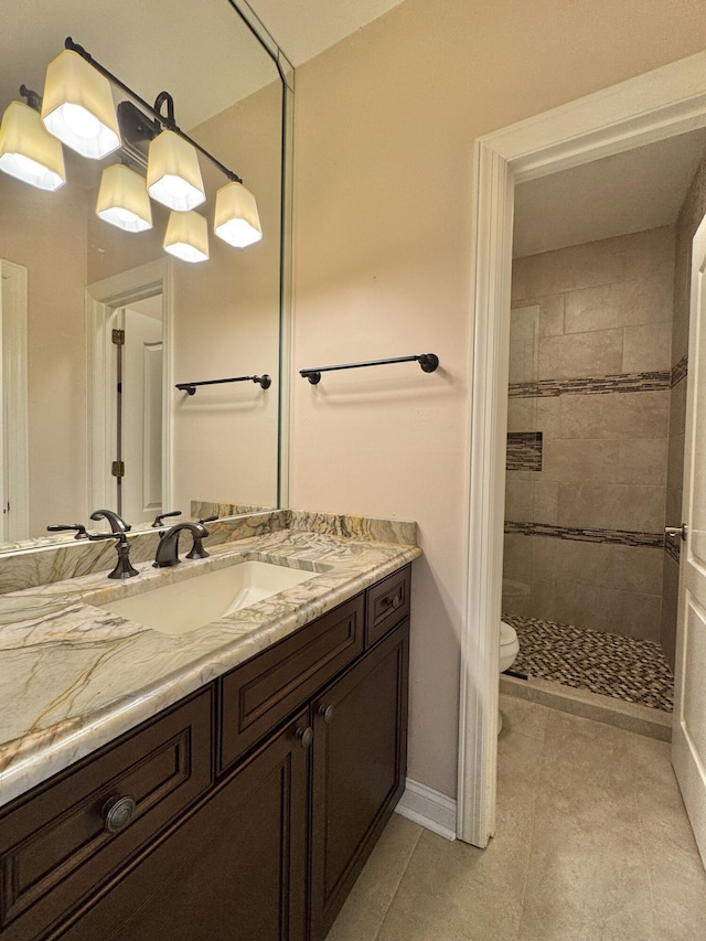 bathroom with tile patterned flooring, vanity, toilet, and tiled shower