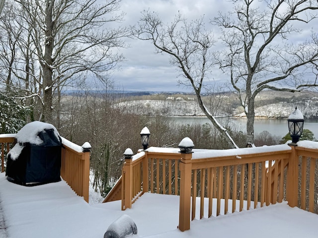 snow covered deck with a grill and a water view