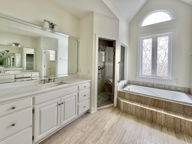 bathroom featuring plus walk in shower, vanity, and lofted ceiling