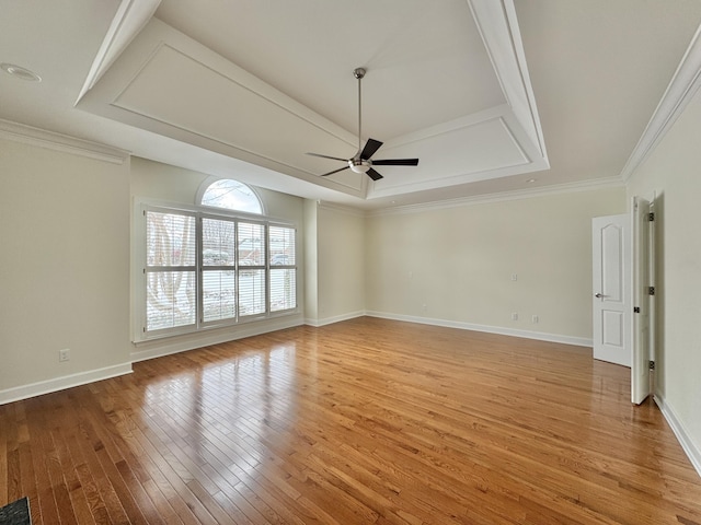 spare room featuring a tray ceiling, ceiling fan, light hardwood / wood-style floors, and ornamental molding