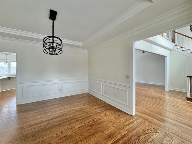 unfurnished dining area with wood-type flooring, ornamental molding, and a chandelier