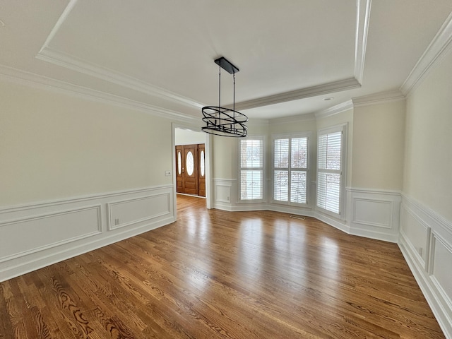 unfurnished dining area with ornamental molding, a notable chandelier, and wood-type flooring