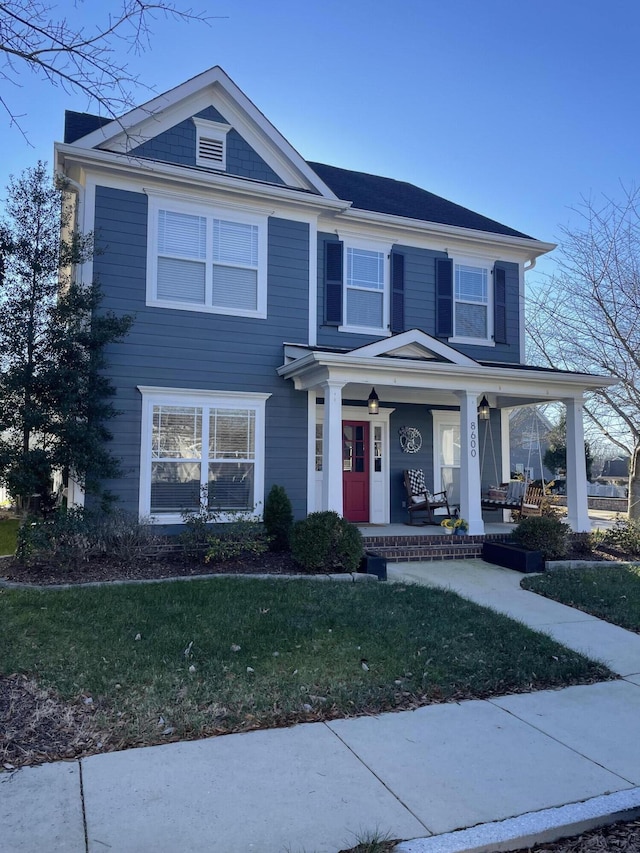 view of front of house with covered porch and a front lawn