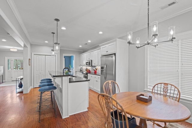 dining room featuring a chandelier, sink, ornamental molding, and hardwood / wood-style floors