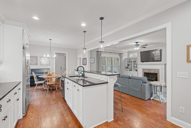 kitchen featuring a kitchen breakfast bar, white cabinetry, decorative light fixtures, and sink