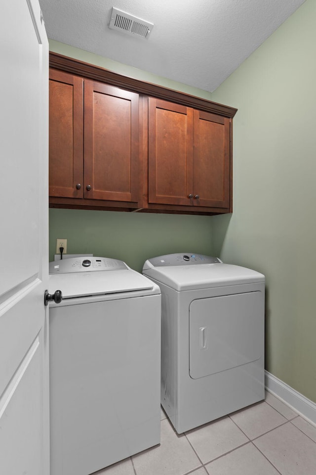 washroom featuring washer and dryer, cabinets, and light tile patterned floors