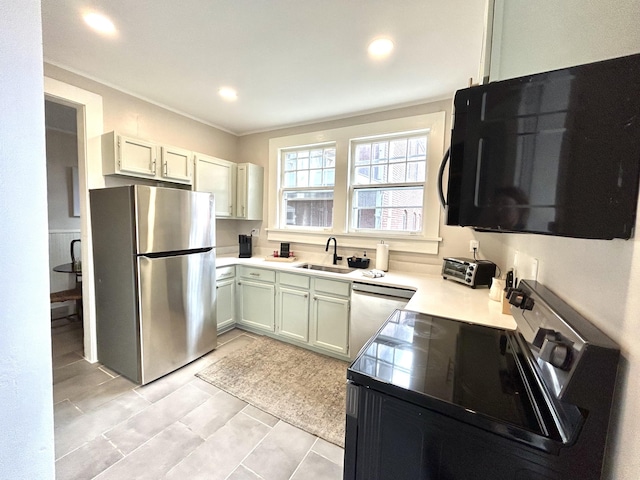 kitchen featuring electric stove, sink, stainless steel fridge, dishwasher, and white cabinets