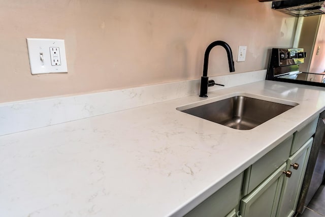 room details with stainless steel electric stove, sink, light stone counters, and green cabinetry