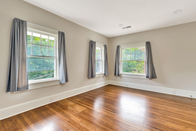 empty room with hardwood / wood-style flooring and a wealth of natural light