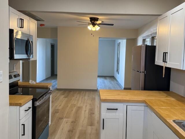 kitchen featuring ceiling fan, white cabinets, appliances with stainless steel finishes, and wood counters