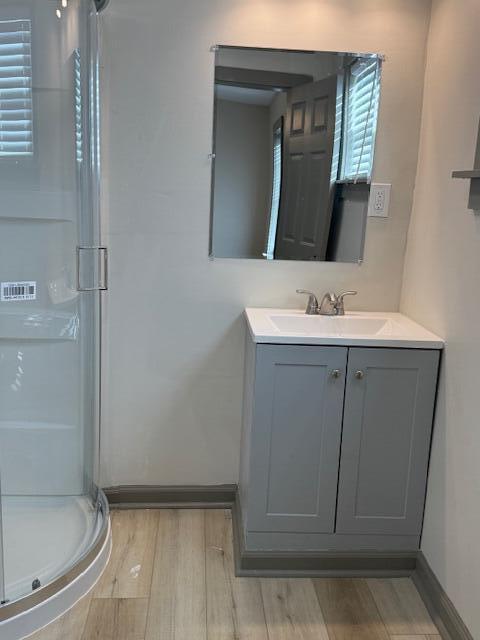 bathroom featuring hardwood / wood-style flooring, a shower with door, and vanity