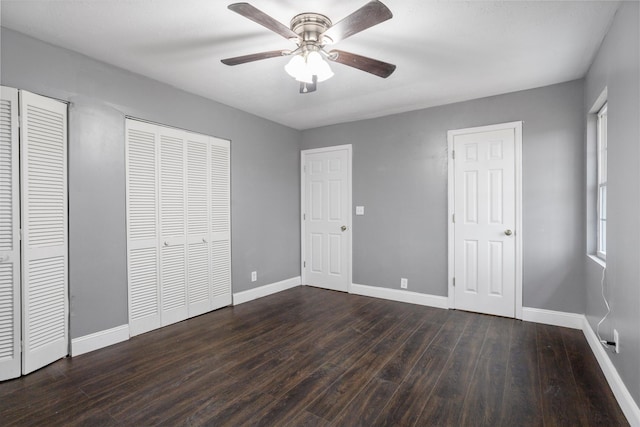 unfurnished bedroom with multiple closets, ceiling fan, and dark hardwood / wood-style floors