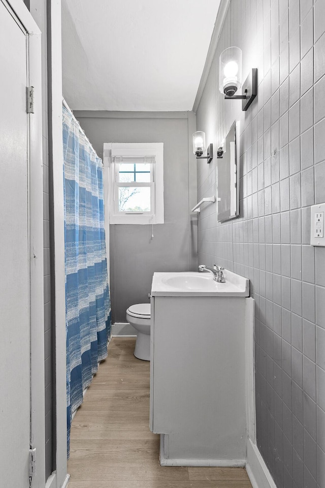 bathroom featuring walk in shower, vanity, hardwood / wood-style flooring, tile walls, and toilet