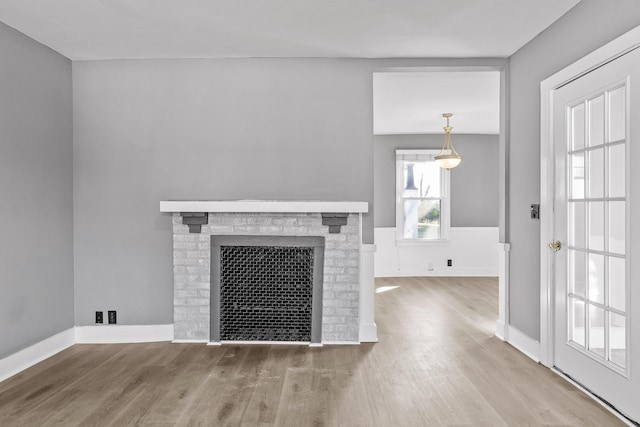 unfurnished living room featuring hardwood / wood-style floors and a brick fireplace