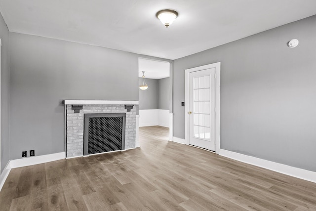 unfurnished living room featuring light hardwood / wood-style flooring and a brick fireplace