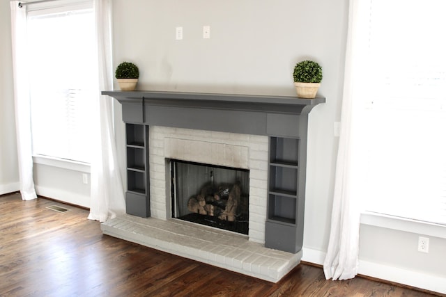 interior details featuring wood-type flooring and a brick fireplace