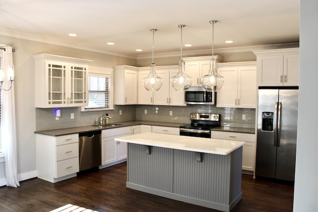 kitchen with stainless steel appliances, a kitchen island, white cabinets, and decorative light fixtures