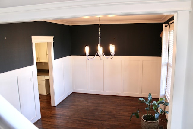 unfurnished dining area with crown molding, dark hardwood / wood-style floors, and an inviting chandelier