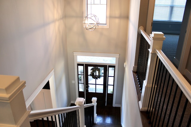 entrance foyer featuring dark wood-type flooring, a notable chandelier, a towering ceiling, and a wealth of natural light